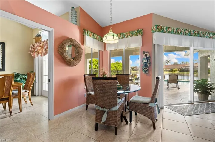 Tiled dining space featuring vaulted ceiling