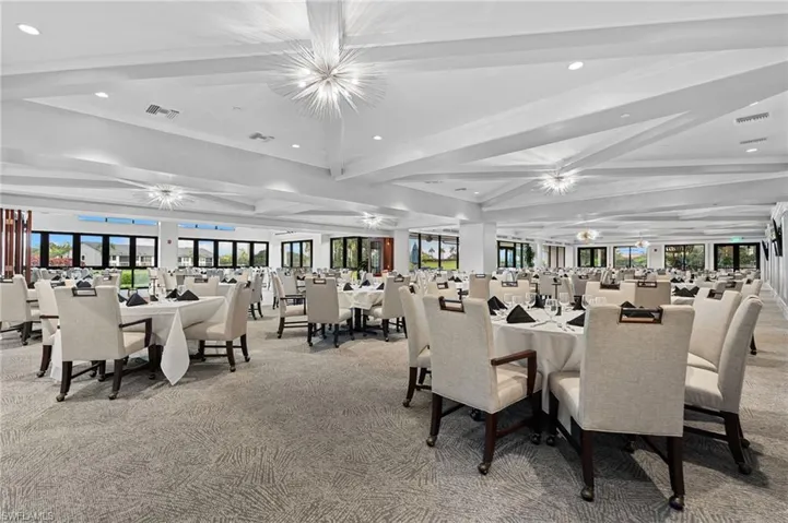 Dining room with beamed ceiling, recessed lighting, healthy amount of natural light, light colored carpet, and a chandelier