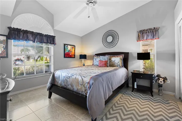 Bedroom featuring lofted ceiling, light tile patterned floors, and ceiling fan