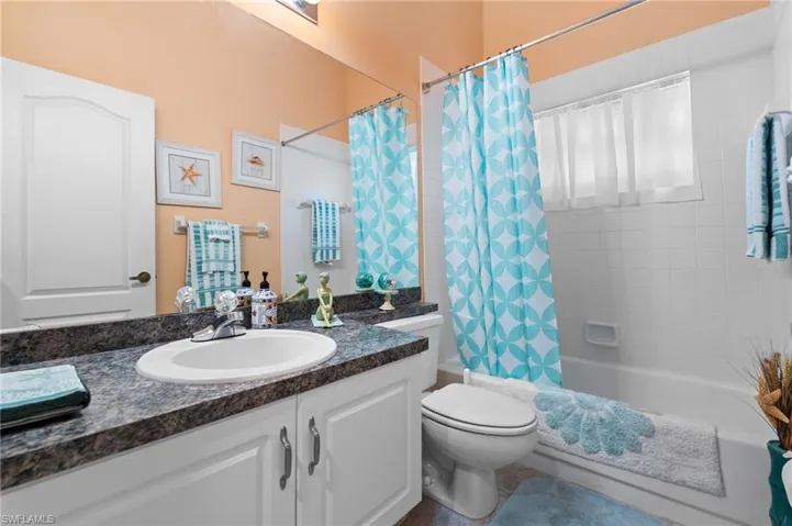 Full bath with shower / tub combo with curtain and vanity