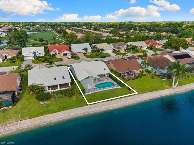 Aerial perspective of suburban area with a nearby body of water and a golf course