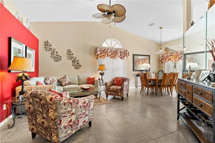 Living room featuring lofted ceiling, ceiling fan, and tile patterned floors