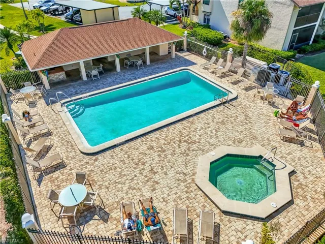 Community pool with a patio area, a fenced backyard, and a hot tub
