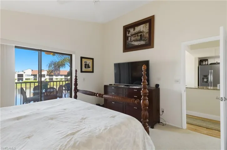 Bedroom with stainless steel refrigerator with ice dispenser, light colored carpet, access to exterior, and a residential view