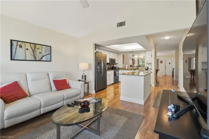 Living area with light wood-type flooring, lofted ceiling, and a chandelier