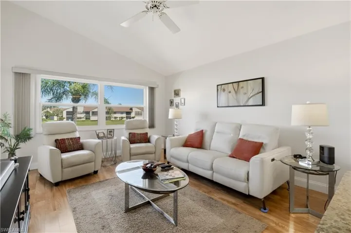 Living room featuring light wood finished floors, lofted ceiling, and a ceiling fan