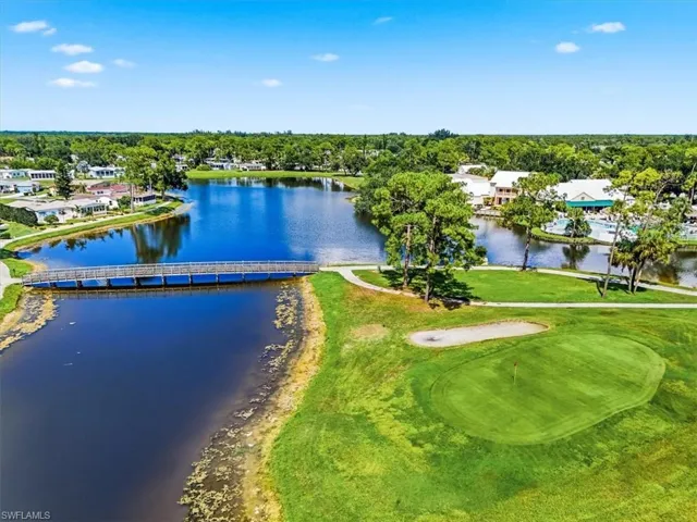 Lush green golf course, tranquil water features, wooden pedestrian bridge, and surrounding residential structures