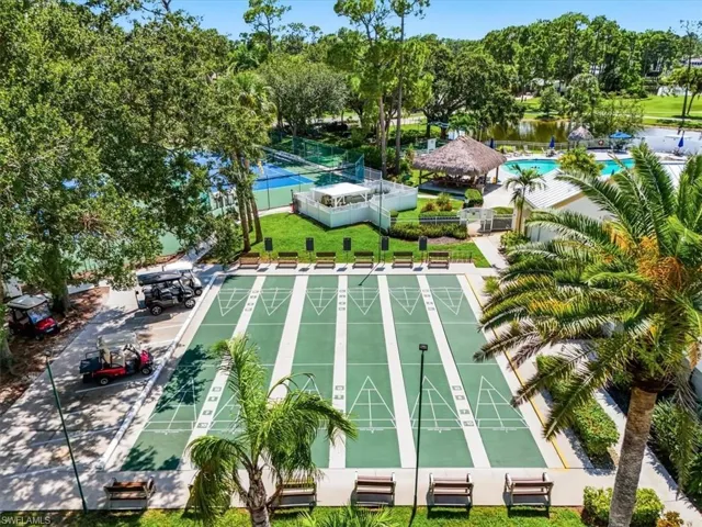 Shuffleboard courts with multiple lanes, tennis courts, an outdoor pool, a tiki-style covered bar, and a water feature