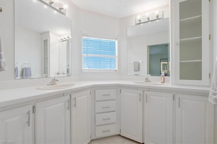 Dual vanity with white cabinetry, integrated sinks, chrome hardware, and wall-mounted mirrors