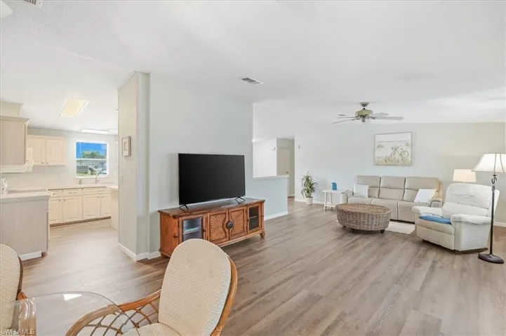 Open-concept living space featuring wood-finish flooring, a ceiling fan, and light-toned wall finishes
