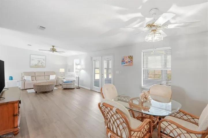 Open-concept living space with wood-finish flooring, white walls, and multiple ceiling fans