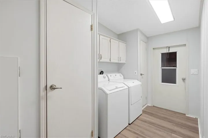 Utility area featuring wood-finish flooring, overhead cabinetry, and a door with an inset window