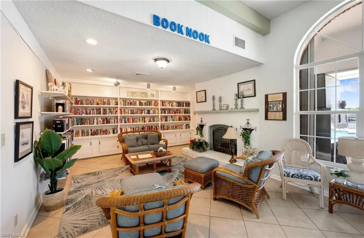 Living area with light tile patterned floors, a textured ceiling, a fireplace, and wall of books