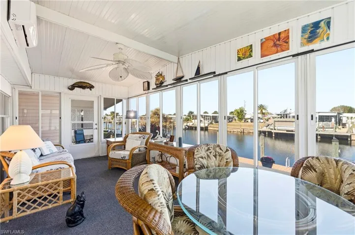 Sunroom / solarium featuring a water view, beam ceiling, and a wall unit AC