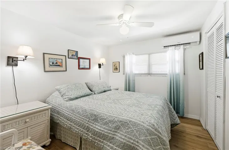 Bedroom featuring a closet, dark wood-style floors, ceiling fan, and a wall mounted air conditioner