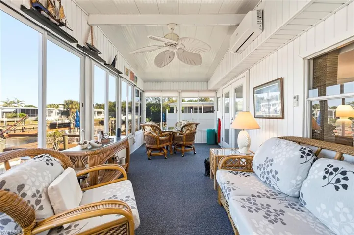 Sunroom with an outdoor hangout area, outdoor dining space, a ceiling fan, a wall unit AC, and beam ceiling