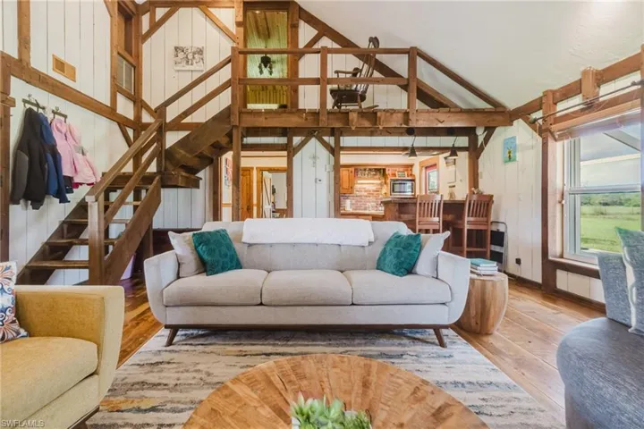 Vaulted ceiling with exposed wood beams, wood-finish flooring, and a built-in loft space