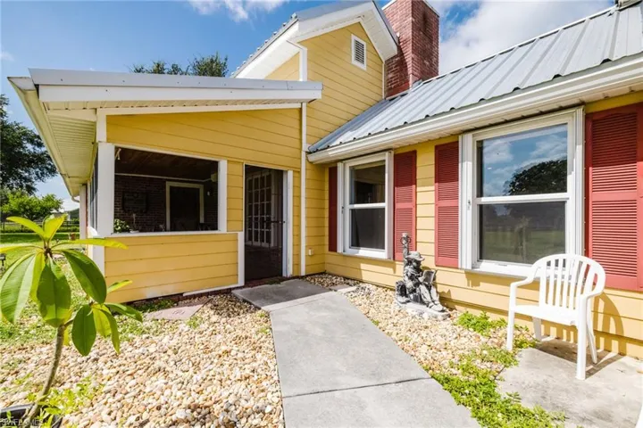 Yellow siding exterior with a screened porch and a concrete pathway