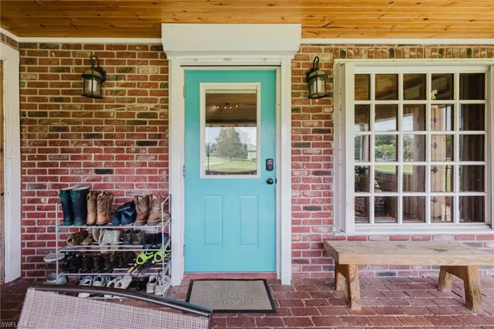 Brick exterior with a wooden porch ceiling, vibrant blue entry door, grid-pattern window, and wall-mounted exterior light fixtures