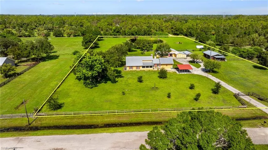 Extensive property featuring a primary residence, multiple auxiliary structures, a substantial pond, and mature landscaping