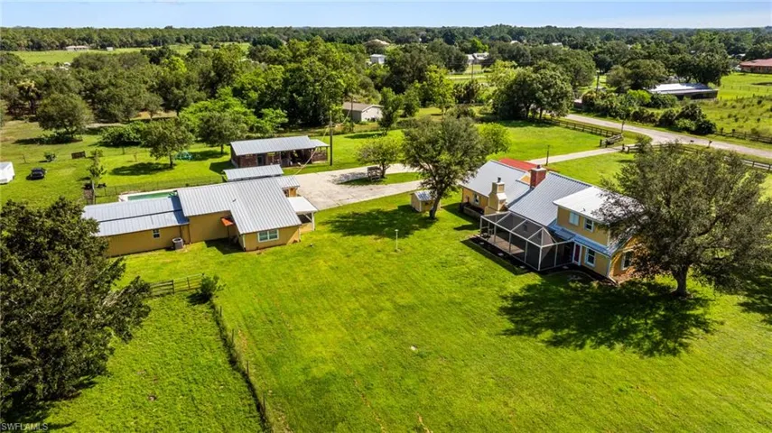 Expansive green lawn, two-story residence with screened porch, additional single-story structure, and multiple outbuildings