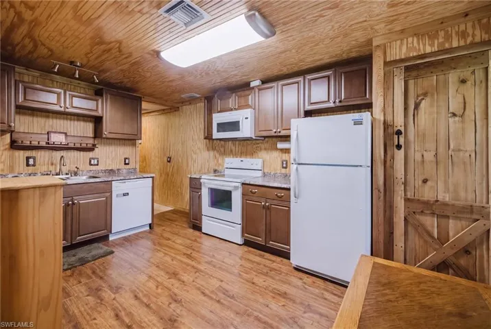 Spacious kitchen featuring wood cabinetry, wood-finish flooring throughout, and stainless steel appliances including refrigerator, range, and microwave