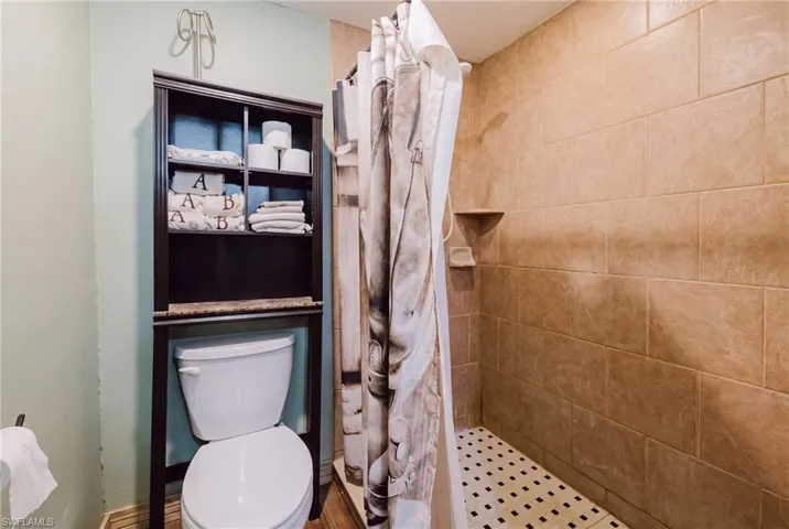 Tiled walk-in shower with a built-in corner shelf and mosaic floor