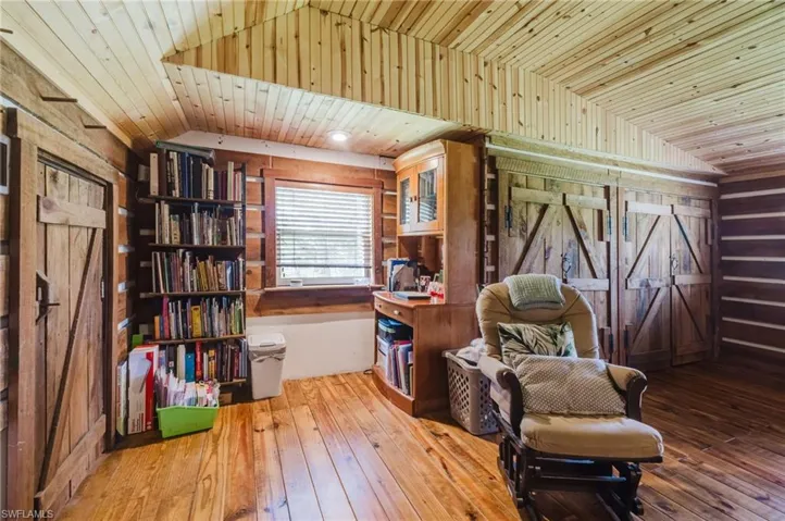 Wood-finish flooring, wood-paneled ceiling, built-in shelving, wood-clad walls, and wood barn doors