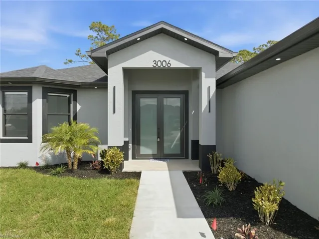 Doorway to property with french doors, stucco siding, a yard, and roof with shingles