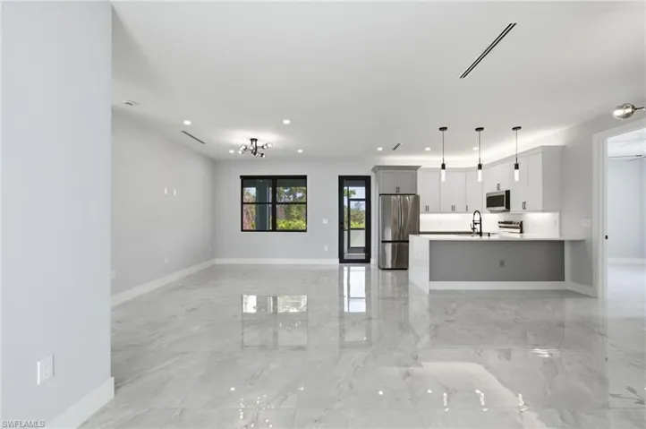 Unfurnished living room featuring light marble finish flooring and recessed lighting