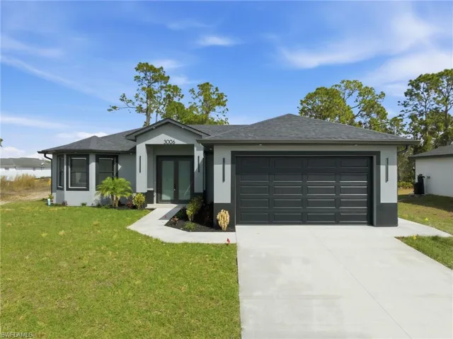 Ranch-style house with a front lawn, french doors, stucco siding, and concrete driveway