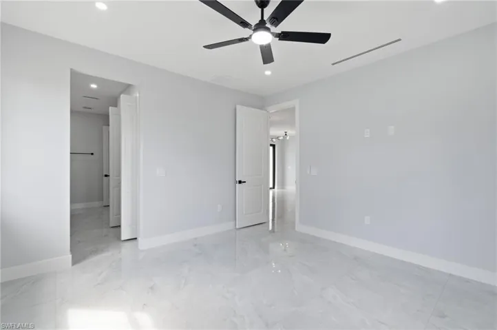 Unfurnished bedroom with recessed lighting, a ceiling fan, light marble finish floors, and ensuite bath