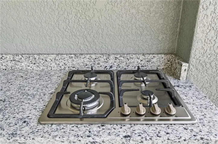 Kitchen view of stainless steel gas stovetop and light stone counters