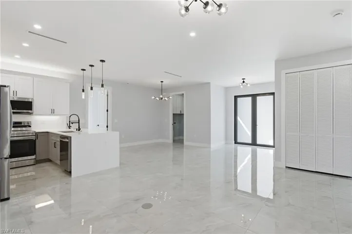 Kitchen featuring hanging lights, stainless steel appliances, light stone counters, open floor plan, and a peninsula