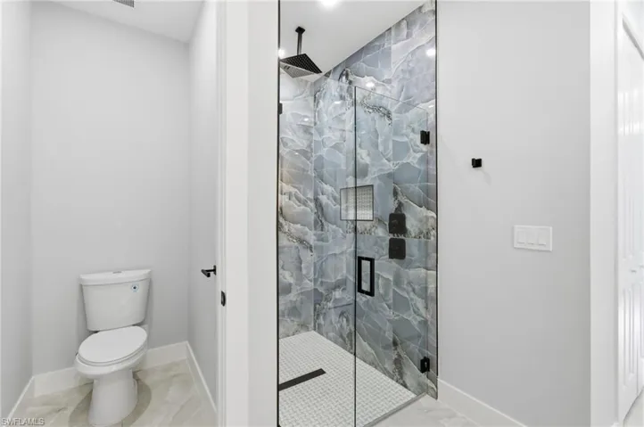 Bathroom with marble look tile flooring and a marble finish shower