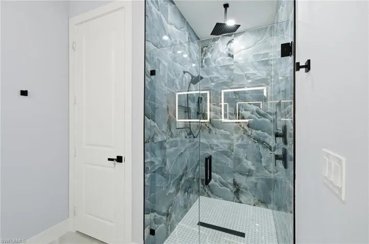 Bathroom featuring a marble finish shower and baseboards
