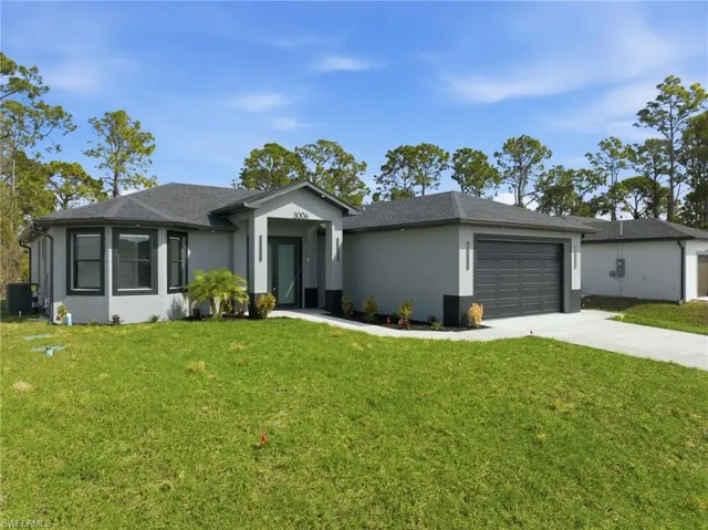 View of front of home featuring a front yard, driveway, an attached garage, and stucco siding