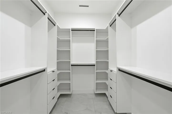 Walk in closet featuring light marble finish flooring