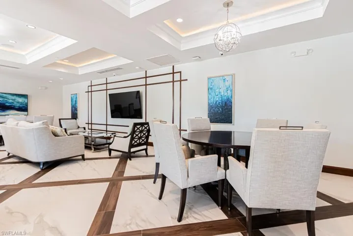Dining area with inlaid floor details, light marble finish floors, a chandelier, coffered ceiling, and a tray ceiling