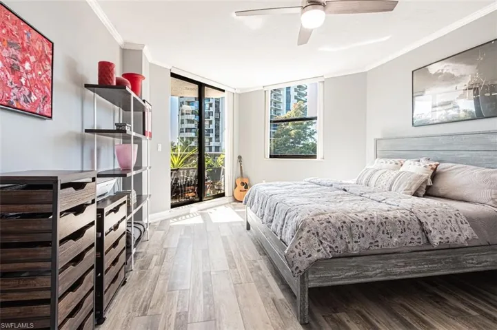 Bedroom with a wall of windows, access to outside, ornamental molding, wood finished floors, and ceiling fan