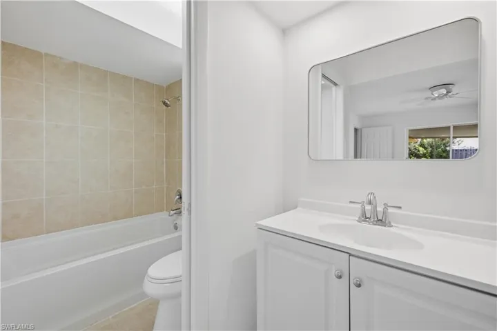 Bathroom featuring a white vanity with integrated sink, chrome faucet, and a rectangular mirror