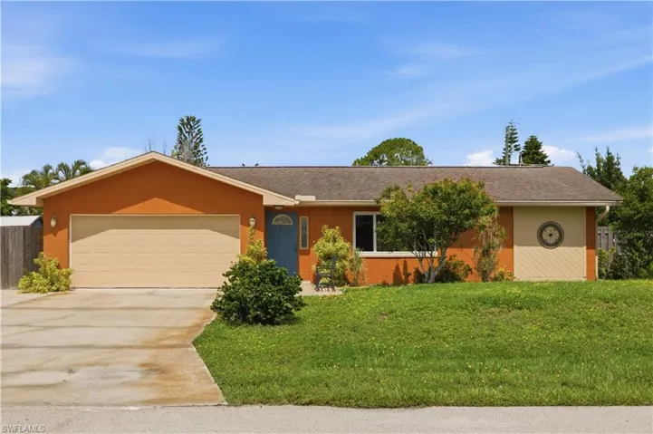 Front exterior with a neutral-toned garage door, a blue entry door, and a circular decorative accent
