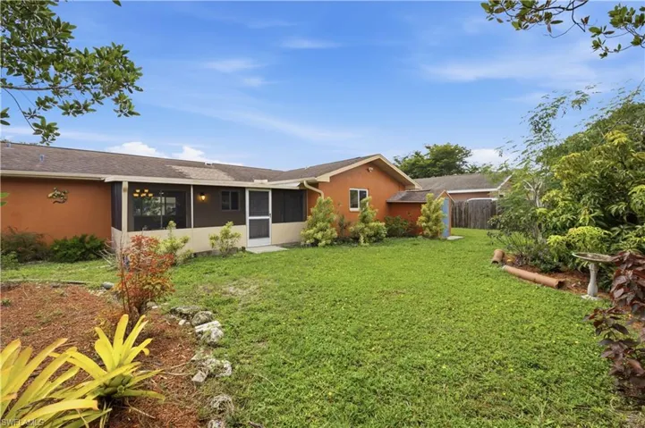 Expansive green lawn with a screened patio featuring an exterior light fixture