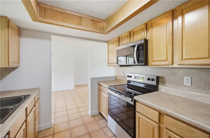 Kitchen featuring wood-finish cabinetry, stainless steel microwave, and stainless steel electric range