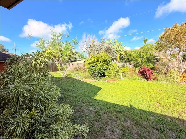 Spacious backyard featuring an expanse of green lawn, established perimeter fencing, and mature trees and shrubs