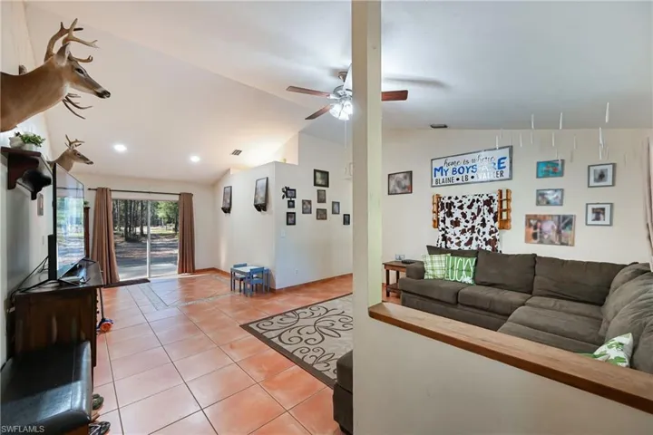 Living area featuring light tile patterned flooring, lofted ceiling, and a ceiling fan