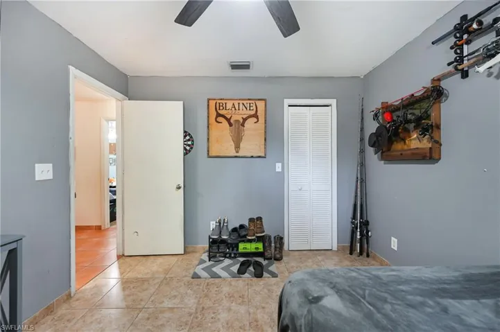 Bedroom with a closet, light tile patterned floors, and a ceiling fan