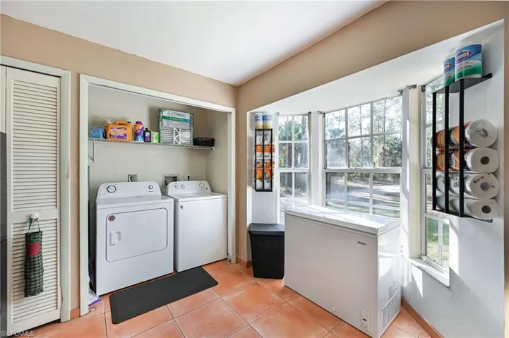Laundry area with washer and clothes dryer and light tile patterned floors