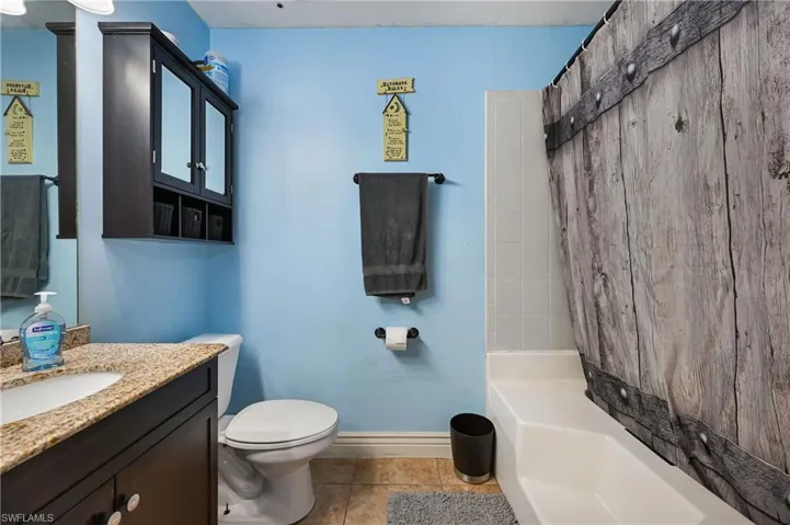 Bathroom with vanity, light tile patterned floors, and bathtub / shower combination