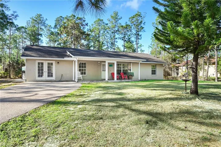 Ranch-style house with stucco siding, french doors, asphalt driveway, and a porch